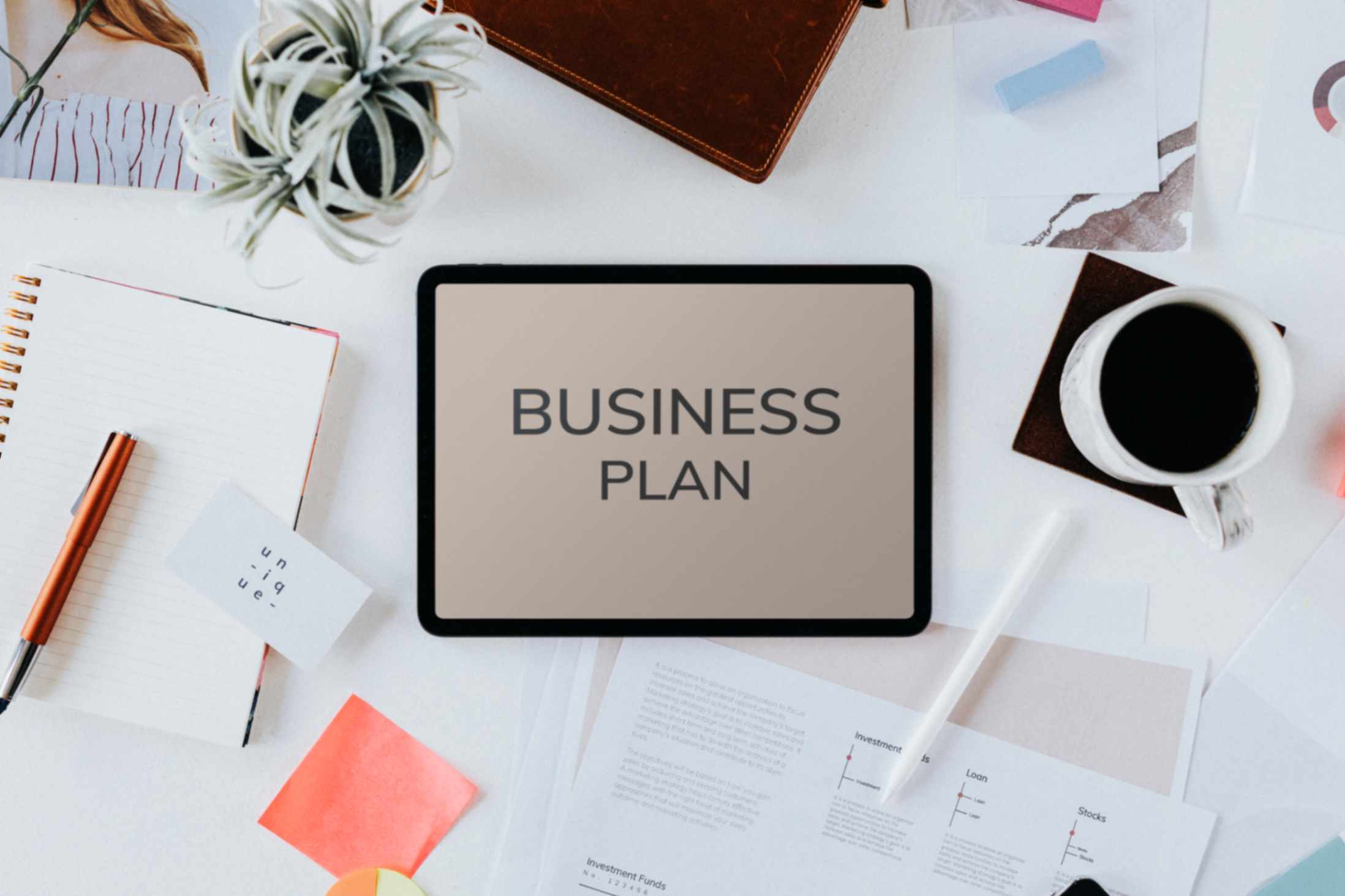 business-plan-on-tablet-surrounded-by-office-supplyments